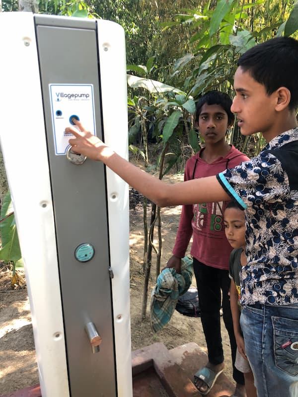Children starting a solar-powered Villagepump with the push button